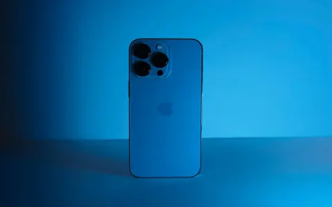Elegancki iPhone 13 granatowy z potrójnym aparatem, lśniącym na tle niebieskiego światła.