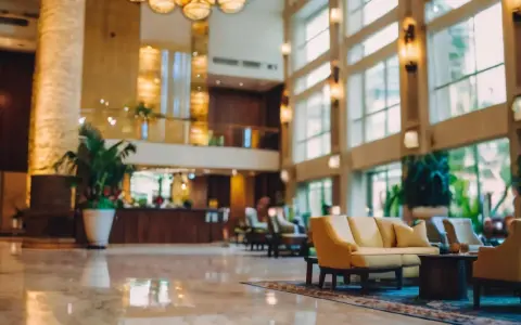 Eleganckie lobby hotelu 10 gwiazdkowego z marmurową podłogą, wygodnymi sofami i bujną roślinnością.