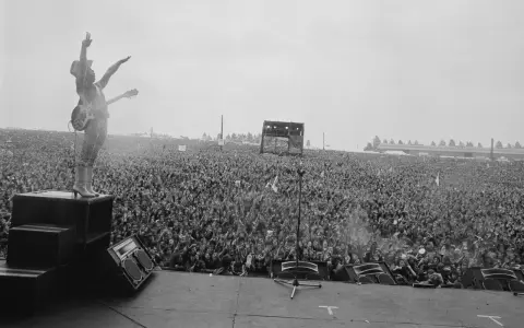 Ogromny tłum na koncercie Metallica Moskwa 1991. Wokalista na scenie, ręce w górze, wita fanów.