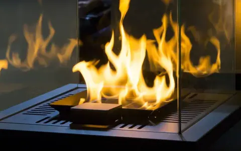 Flammen tanzen in einem modernen, gläsernen Kamin. Ein stilvoller holzofen ohne schornstein, der Wärme und Gemütlichkeit ausstrahlt.