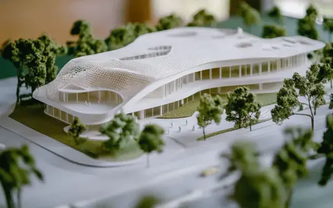 A 3D printed architectural model showcases a futuristic building with a flowing roof, demonstrating how to use 3d printing in architecture for complex designs.