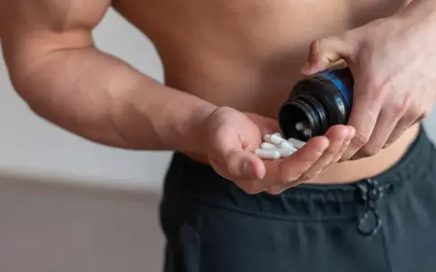 Muskulöser Mann nimmt Kapseln ein, um die BCAA Wirkung für den Muskelaufbau zu nutzen.
