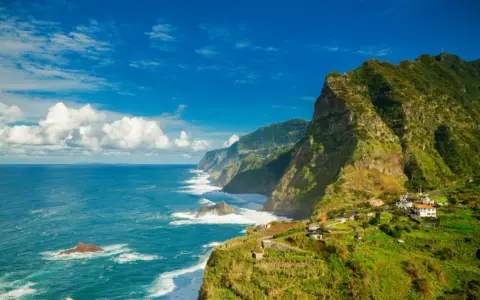 Grüne, steile Küsten mit kleinen Häusern, die sich an den Hang schmiegen. Das azurblaue Meer brandet an Felsen. Ja, Madeira in der EU bietet diese atemberaubende Aussicht.