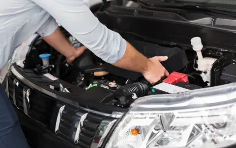 Meccanico controlla il motore per problemi al motorino d'avviamento.