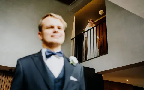 Pan młody w garniturze i panienka młoda w bieli na balkonie. Zastanawiasz się, ile bierze fotograf za wesele?