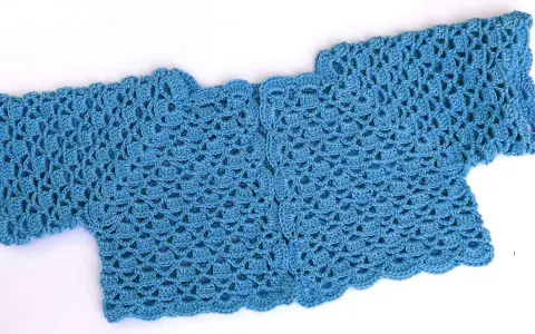 Bolero crochet azul con un delicado patrón de escamas y borde ondulado.
