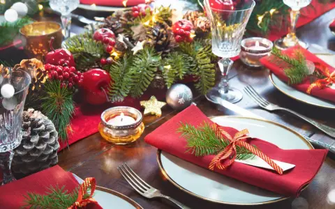 Vackert dukat på julbordet med röda servetter, granris och julgranskulor.