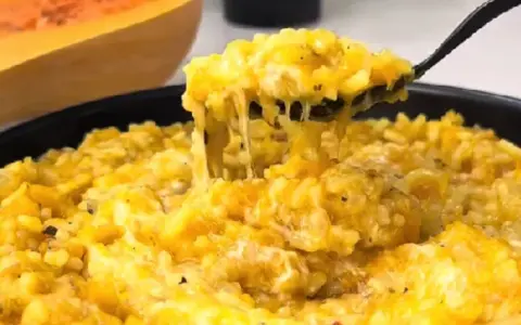 Risotto cremoso de calabaza en un plato, con una cuchara sacando una porción.