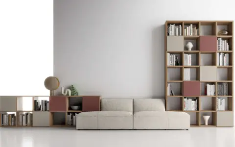 Un comodo divano beige è posizionato davanti a una libreria modulare in legno, con libri e oggetti decorativi.