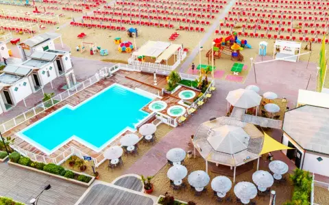 Vista aerea del lido delle sirene Cattolica: piscina, vasche idromassaggio, lettini rossi e ombrelloni sulla spiaggia.