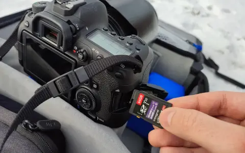 Dłoń wkłada kartę pamięci 64GB do aparatu. Ile to zdjęć? Z pewnością mnóstwo!