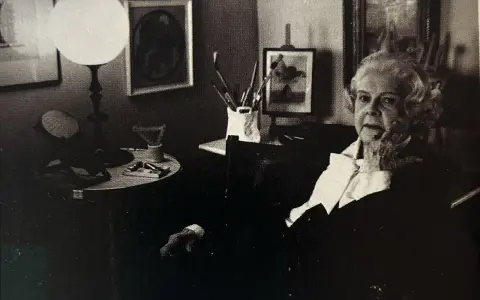 Colette Gueden, artiste peintre, dans son atelier, entourée de ses œuvres et de son matériel.