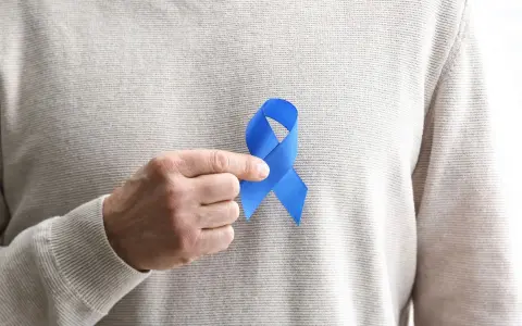 Mężczyzna trzyma niebieską wstążkę symbolizującą świadomość raka prostaty. Rozważamy usunięcie prostaty skutki.