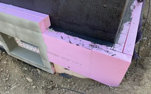 Dämmung wird angebracht. Pinke Styrodurplatten werden sorgfältig an die Wand geklebt, um das Gebäude zu isolieren.