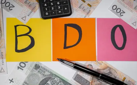 BDO - litery na kolorowych kartkach, obok kalkulator i polskie banknoty. Kto nie musi, niech nie liczy.