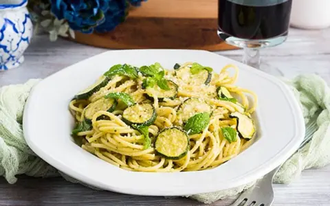 Un piatto di pasta e zucchine alla siciliana, guarnito con menta fresca e parmigiano.