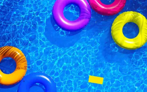 Colorful inflatable rings float in a sparkling blue pool, hinting at how to get crystal clear pool water.