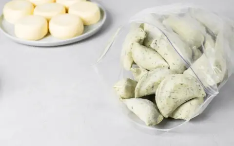 Mrożone pierogi w woreczku obok talerza z okrągłymi serkami.