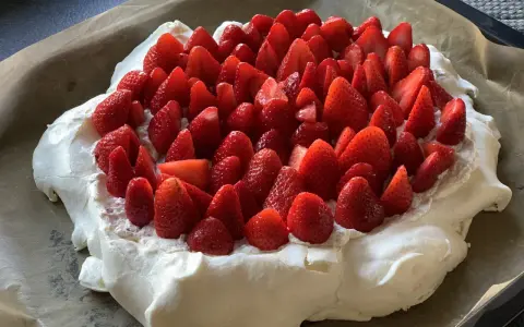 En stor pavlova i långpanna, täckt med vispgrädde och massor av färska jordgubbar. Perfekt för sommarens firanden!
