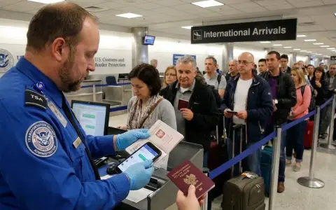 Kontrola paszportowa na lotnisku w USA. Urzędnik TSA sprawdza dokumenty podróżnych, wśród których widać osoby z polskimi paszportami.
