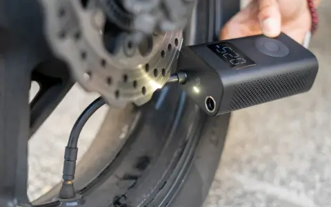 Gonfleur de pneu sans fil connecté à la valve d'une roue de moto, affichant la pression.