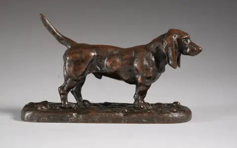 Une sculpture en bronze d'un chien basset hound, une des œuvres d'art de Antoine-Louis Barye, sur un socle imitant le sol.