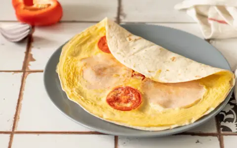 Pyszna tortilla z jajkiem, pomidorem i szynką, gotowa do zjedzenia.