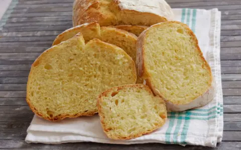 Fette di pane di semola dorato, con la crosta croccante e la mollica soffice, su un canovaccio a righe.