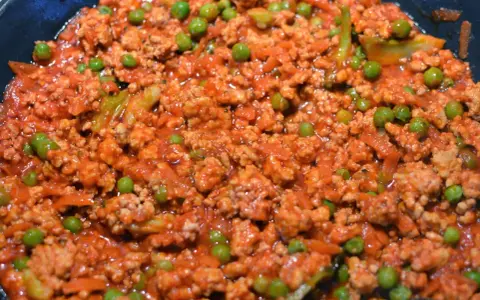 Pyszne spaghetti con piselli z mielonym mięsem i groszkiem w sosie pomidorowym.
