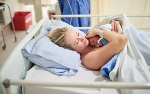 Szczęśliwa mama tuli noworodka. To początek jej urlop macierzyński, pełen miłości i czułości.