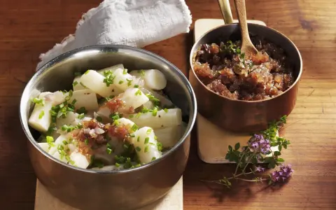 Ein köstliches Haferwurzel Rezept mit karamellisierten Zwiebeln und frischem Schnittlauch. Serviert in Kupfer- und Edelstahlschalen auf einem Holztisch.