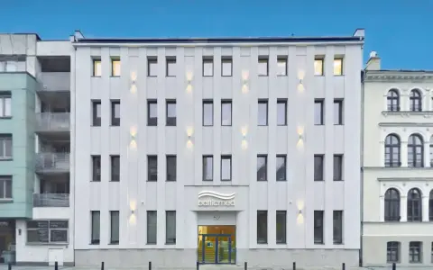 Nowoczesny, biały budynek kliniki Balticmed w Szczecinie z podświetlanym logo i oknami.