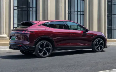 Czerwony luksusowy SUV Denza N9 widziany z boku, na tle budynku z kolumnami.