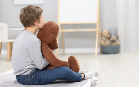 Chłopiec z autyzmem przytula misia. Zastanawiasz się, ile wynosi subwencja na dziecko z autyzmem?
