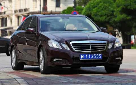 Ciemnobrązowy Mercedes z tablicą W 113555, wskazującą na rejestracje dyplomatyczne.