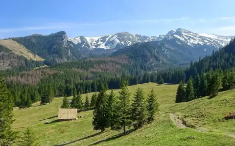 Piękne podkarpackie góry z ośnieżonymi szczytami, zielonymi halami i lasami. Na pierwszym planie drewniana szopa.