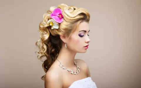 Elegancka, naturalna fryzura na wesele z lokami i kwiatami. Delikatne fale i ozdoby podkreślają urodę panny młodej.