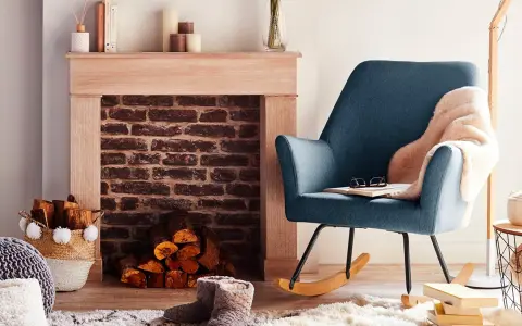 Un fauteuil bleu confortable invite à la détente près d'une cheminée en briques, créant un coin cheminée cocooning parfait pour lire.