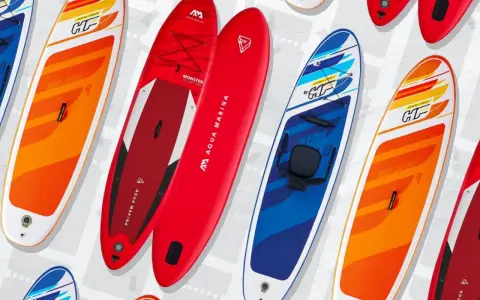 Bunte SUP-Boards, auch Stand-Up-Paddleboards genannt, liegen nebeneinander. Sie sind für Wassersportler gedacht.