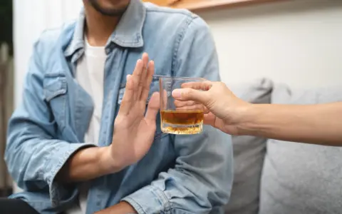 Mężczyzna odmawia alkoholu, symbolizując dobrowolne leczenie odwykowe i nowy początek.