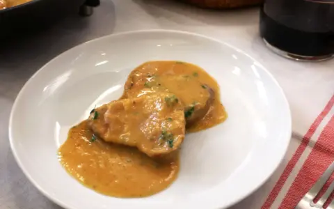 Dos medallones de solomillo al ajillo en una salsa cremosa, servidos en un plato blanco.