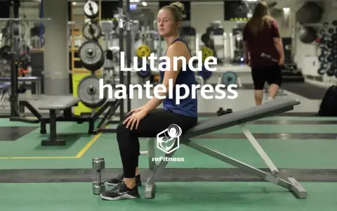 Kvinna förbereder sig för lutande hantelpress på gym. En hantel ligger bredvid henne.