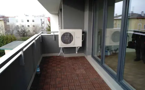 Klimatyzacja w bloku zamontowana na balkonie. Jednostka zewnętrzna chłodzi mieszkanie, zapewniając komfort.