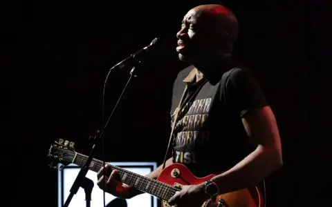 Musiker mit Gitarre und Mikrofon, trägt T-Shirt mit dem Titel von Otis Redding.