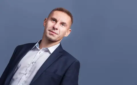 Mężczyzna w garniturze i białej koszuli, patrzący w górę.