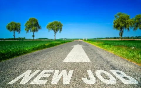 Strada asfaltata con freccia bianca e scritta "NEW JOB". Un percorso verso un futuro luminoso, ideale per chi sta pensando di cambiare lavoro a 30 anni.