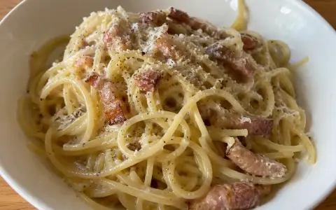 En krämig portion pasta carbonara med knapriga bitar av fläsk och rikligt med svartpeppar.