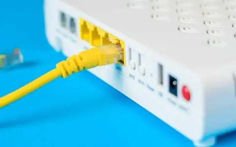 Żółty kabel sieciowy podłączony do portu LAN routera i modemu.