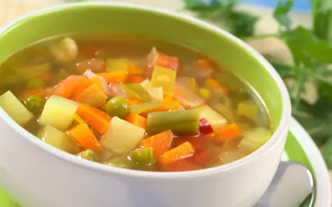 Miseczka pełna warzyw, idealna na dietę zupową. Marchewka, ziemniaki, groszek i fasolka w aromatycznym bulionie.