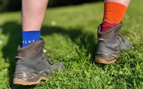 Falke TK1, TK2, TK3, TK4 Socken in Blau und Orange, getragen mit Wanderschuhen im Gras.